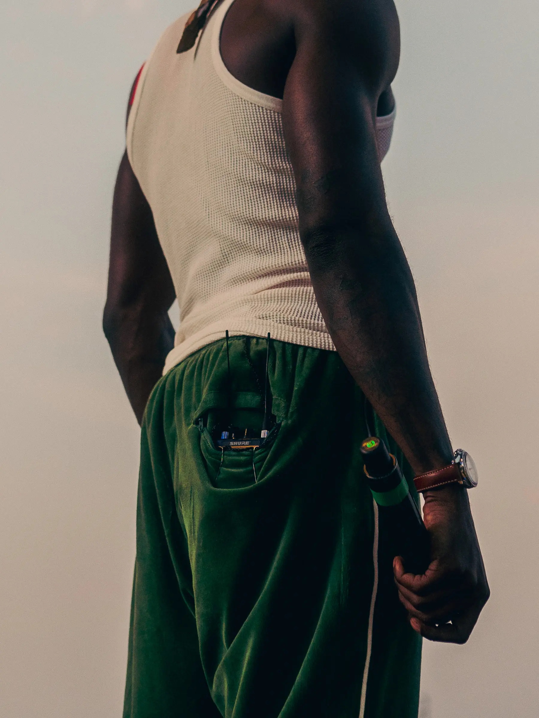 Detail shot of Kojey Radicals Clothing: A white vest and blue denim jeans